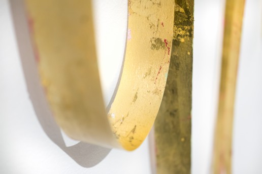 Detail of gold foil with small markings of magenta flashe paint